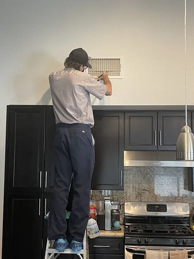 Technician inspecting an air vent during HVAC service in Boulder Creek